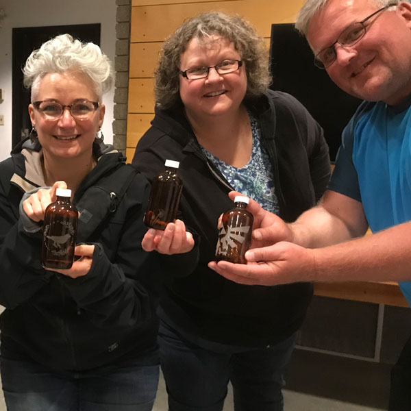 Three adults holding bottles up